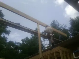 Carpenter setting a ridge beam over a new addition frame — Ice Dam Removal by Roofing Brothers in Sharon Center