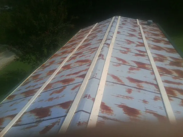 Rusted metal roof panels with new wood purlins before replacement — Storm Damage Roof Repair in Sharon Center by Roofing Brothers
