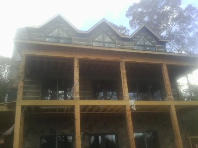 Dormers and porch framing on a large log home under construction — Roof Coating work by our crew in Sharon Center