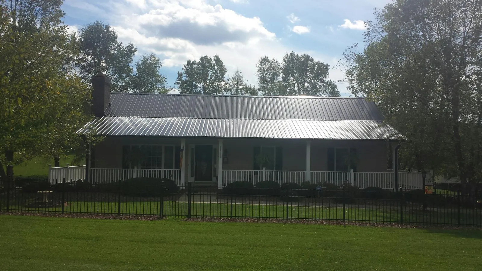 Gray metal roof on a brick ranch with a full width front porch — Gutter Guard Installation work by our crew in Sharon Center