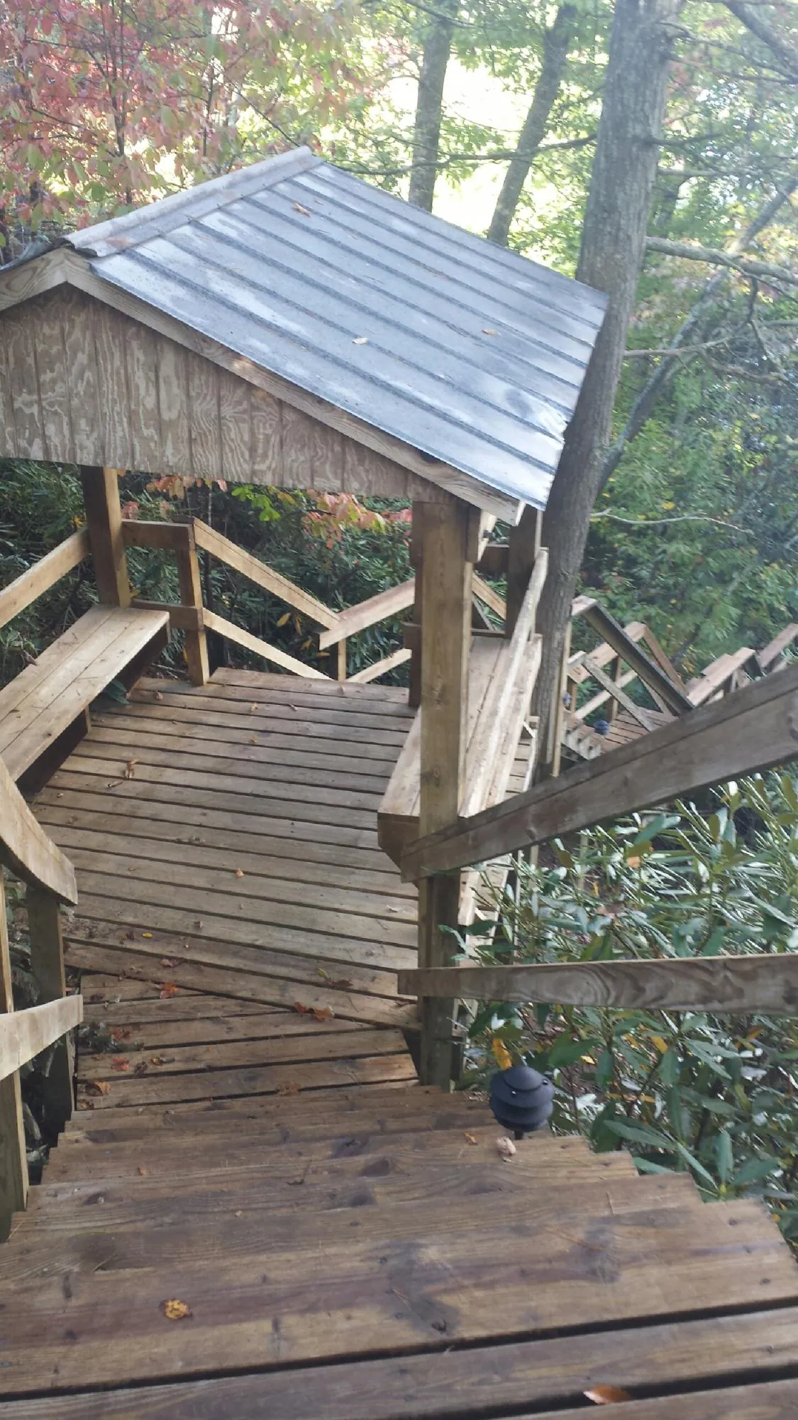 Metal roofed shelter over wooden steps on a wooded walkway — Skylight Repair & Installation work by our crew in Sharon Center