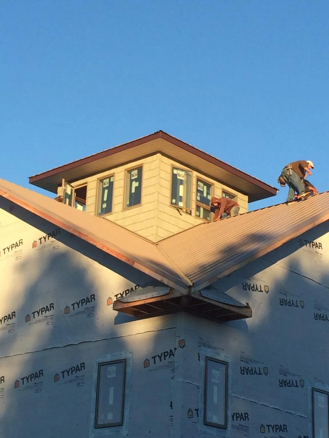 Roofers working around a rooftop cupola on a new metal roof at sunset — Roof Waterproofing in Sharon Center by Roofing Brothers